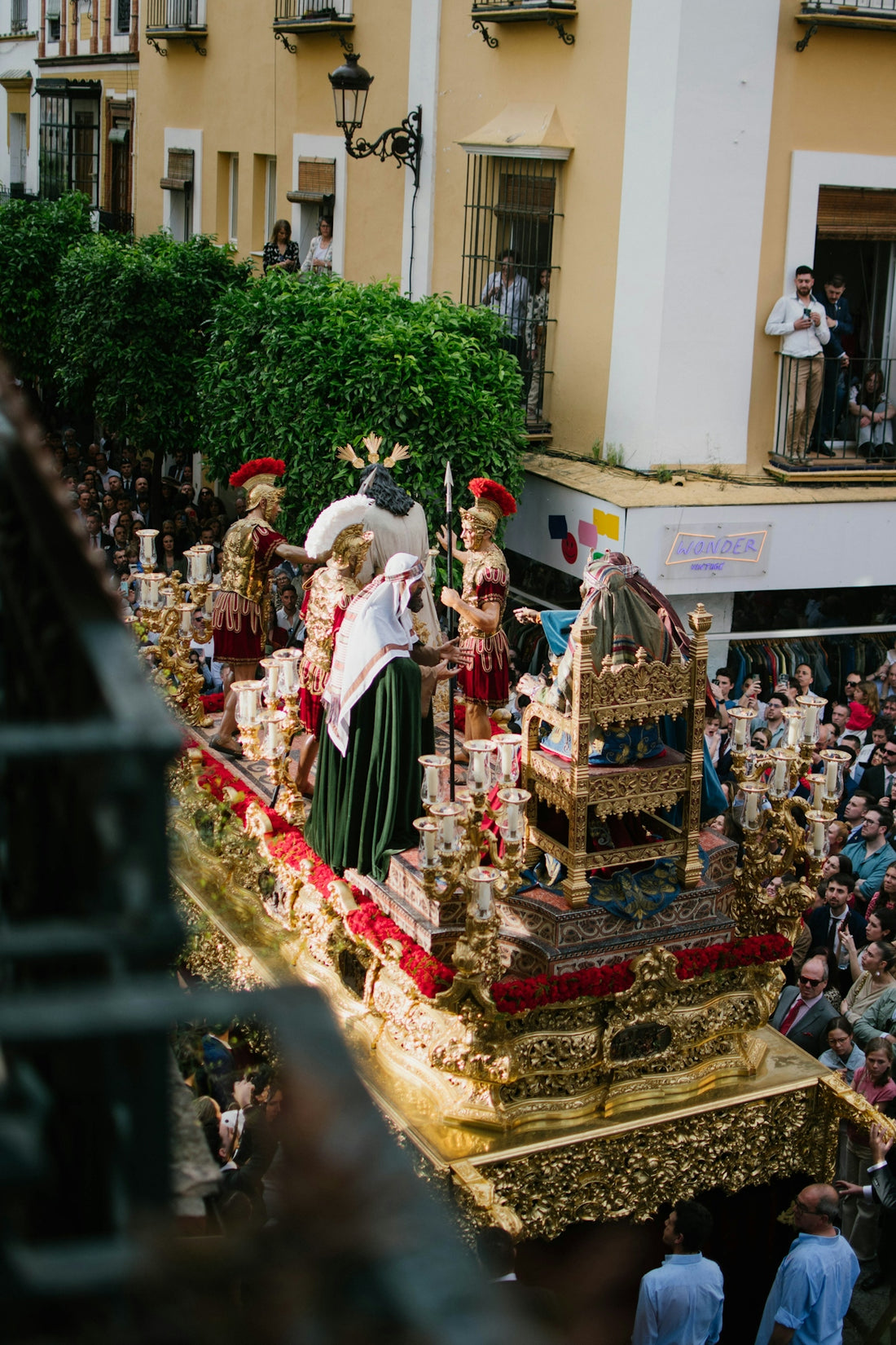 A religious procession moves through a narrow street